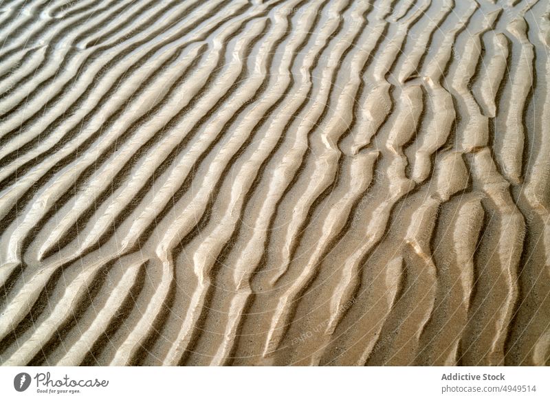 Rippling surface of dry sand ripple texture beach summer uneven rough background shore wave seaside desert climate arid drought brown barren terrain dune curve