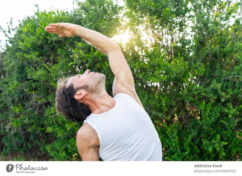Male doing Reverse Warrior pose in summer man yoga session park balance reverse warrior pose arm raised backbend stretch male calm middle age mature barefoot