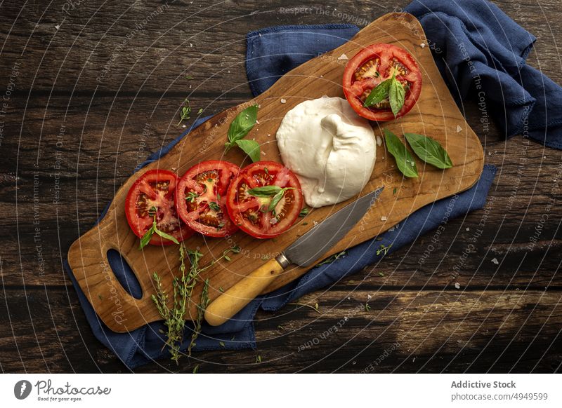 Appetizing fresh tomato and mozzarella cheese with herbs on wooden board cutting board basil healthy food vegetable meal thyme leaf delicious knife slice yummy