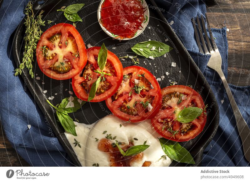 Delicious dish with tomatoes cheese and herbs on tray burrata sauce basil thyme mozzarella delicious vegetable appetizing cloth salt fork yummy product leaf