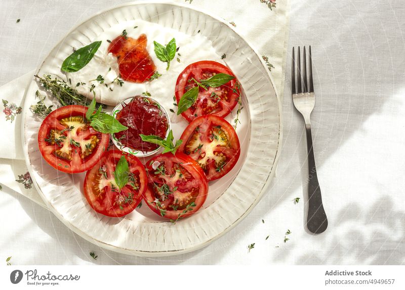 Healthy lunch with fresh tomatoes and mozzarella cheese with herbs and sauce dish food italian cuisine portion restaurant delicious nutrition basil thyme fork