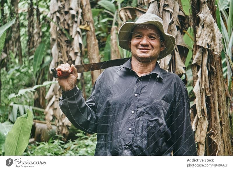 Hispanic farmer with machete in jungle man banana ecology smile work agriculture portrait costa rica male blade knife hispanic ethnic bucket hat shirt cheerful