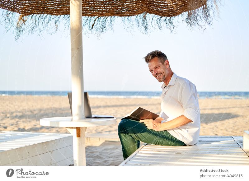 Businessman taking notes on beach businessman take note write planner telework sea smile project data delight male freelance distance summer notebook vacation