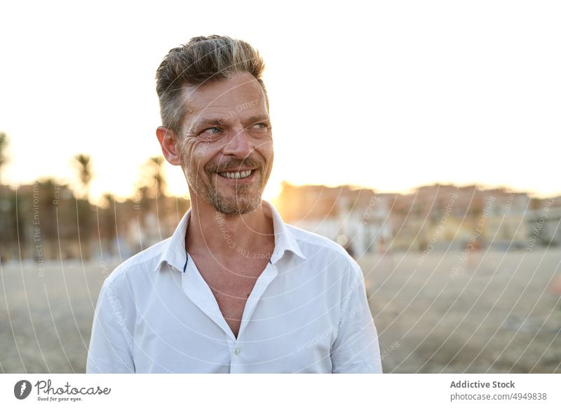 Happy mature man on beach at sunset smile vacation summer weekend happy resort portrait male cheerful middle age positive sundown glad content carefree seashore