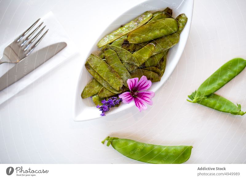 Grilled snow peas with flowers roast plate lunch serve garnish table vegan silverware dish fresh nutrition healthy food edible fork knife delicious tasty