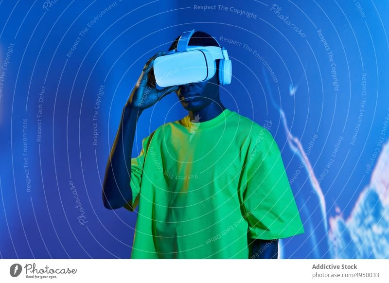 Young African American male watching video in VR goggles man virtual reality concentrate immerse vr experience explore futuristic cyberspace simulate young