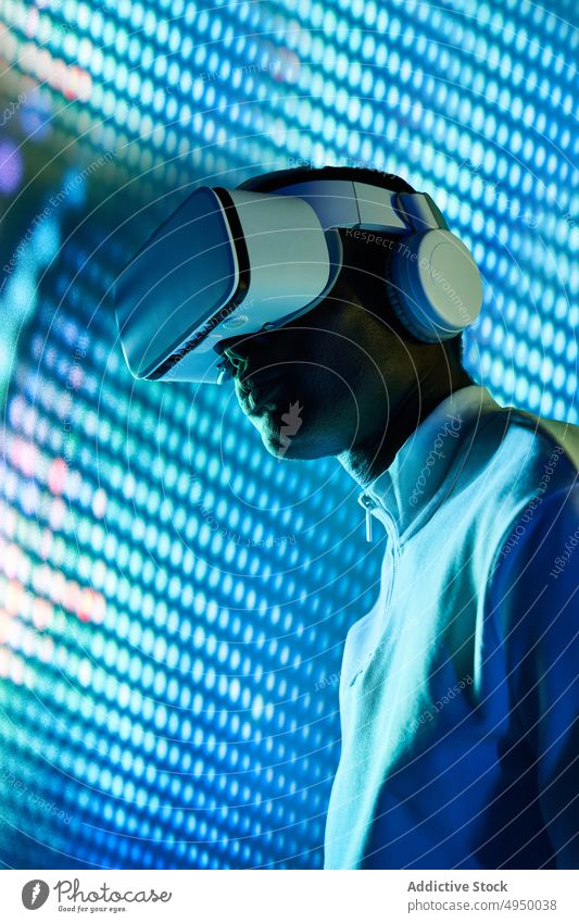 Serious black man touching large screen while exploring virtual reality in modern headset explore concentrate futuristic vr neon cyberspace entertain digital