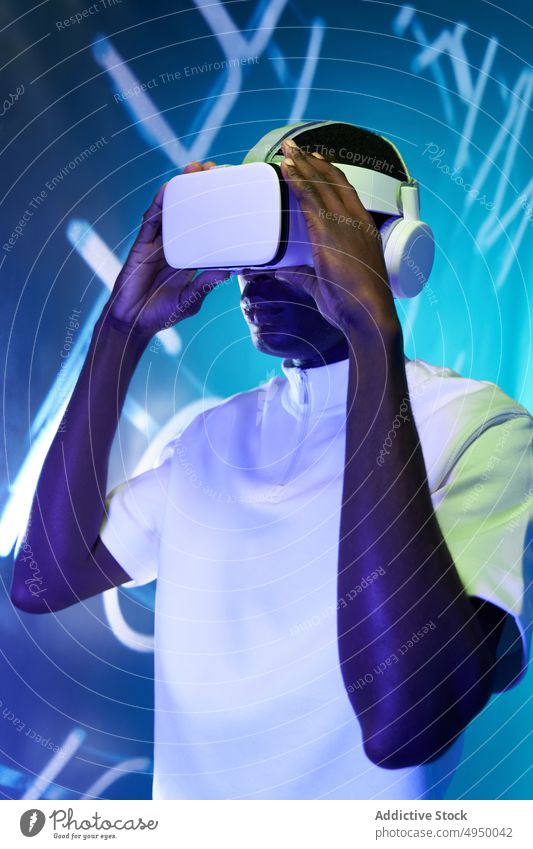Young African American male watching video in VR goggles man virtual reality concentrate immerse vr experience explore futuristic cyberspace simulate young