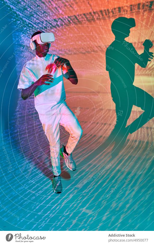 Attentive black male walking in futuristic space in VR goggles man virtual reality explore vr cyberspace simulate immerse digital hi tech projector young
