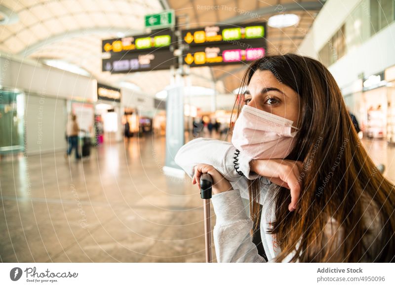 Bored woman waiting for flight in airport terminal travel tourist lean suitcase epidemic bored female young brunette face mask passenger pandemic covid 19