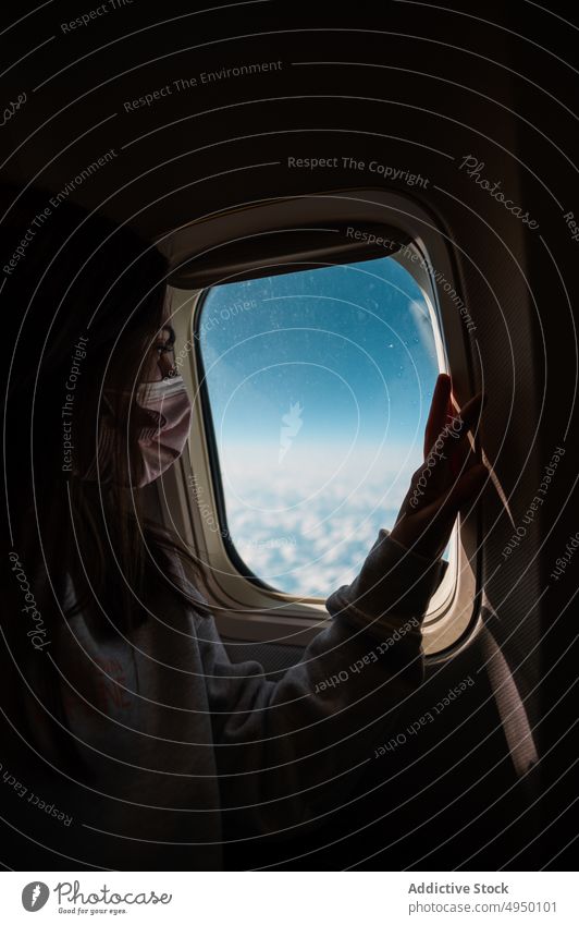 Female traveler looking out window woman plane blue sky cloudy dark cabin vacation pandemic female passenger covid19 aircraft new normal admire flight face mask