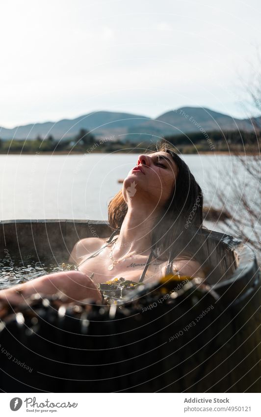 Female taking seaweed bath near lake woman rest barrel thoughtful shore calm spa resort female pensive young weekend water eyes closed relax summer daytime
