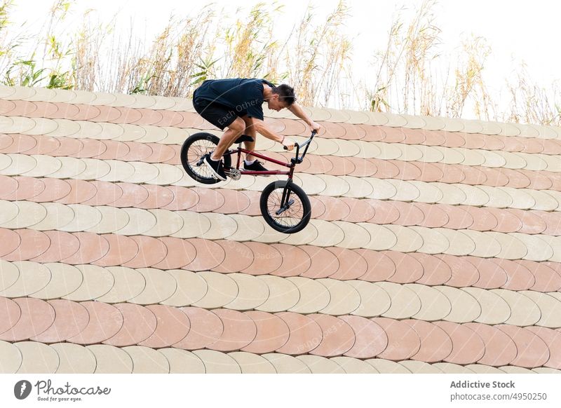 Young male riding BMX bike down slope man ride bmx bile skate park trick wallride weekend hobby summer activity cyclist energy bicycle motion grass stunt