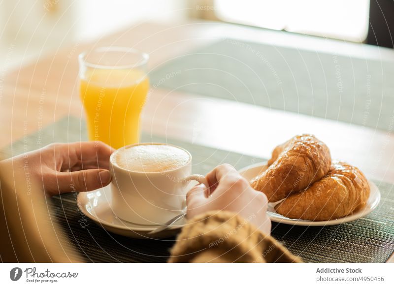 Anonymous woman having breakfast in restaurant coffee juice croissant table female beverage weekend casual sweater cafe cafeteria lifestyle coffee shop sit