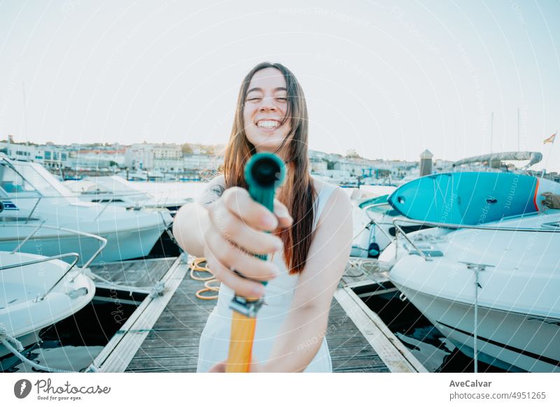 A young cheerful woman cleaning a classic sailing yacht with sweet water after sailing in the mediterranean sea. Luxury travel and lifestyle concept. ship