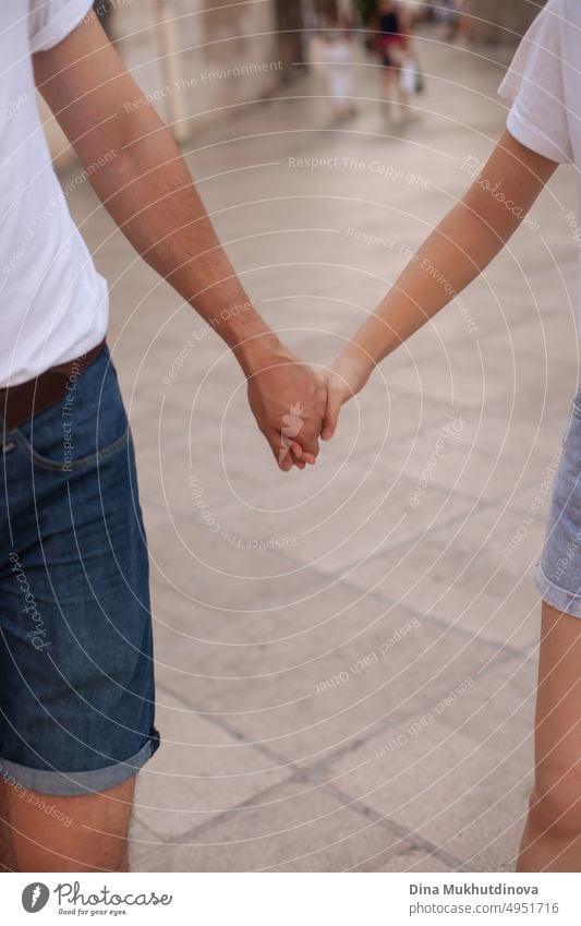 Interracial couple holding hands. Diverse people holding hands on a walk in the city. Love and friendship. Bonding. Holding together. young guy and girl holding hands.