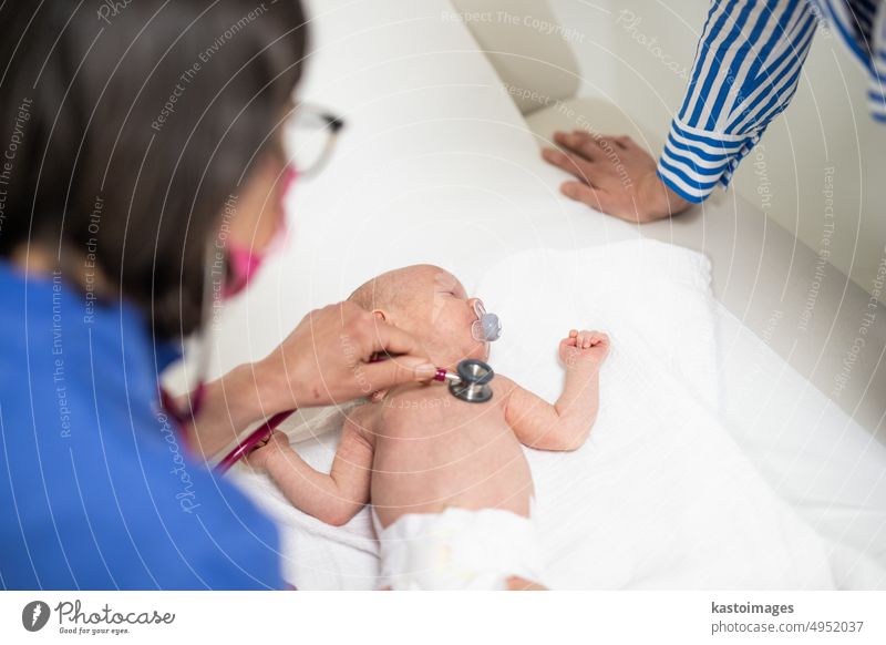 Baby lying on his back as his doctor examines him during a standard medical checkup. baby infant boy pediatrician stethoscope heartbeat childhood medicine