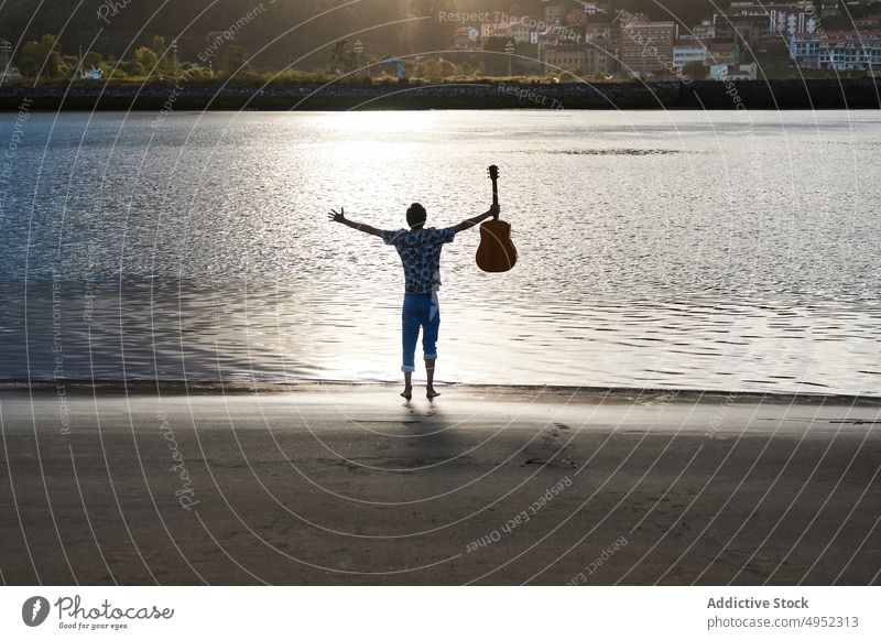 Carefree male musician with guitar standing on seashore man beach carefree freedom summer enjoy guitarist acoustic wet outstretch harmony water coast guy