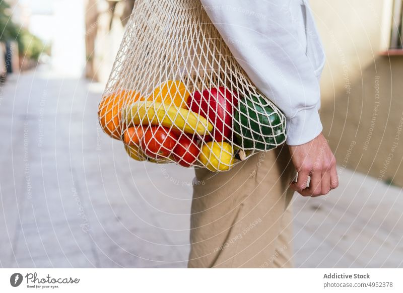 Anonymous man with fruits in mesh bag in city eco friendly street grocery natural zero waste male organic urban ripe fresh shopper shopping bag healthy food
