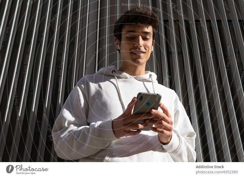 Smiling man using smartphone in city message social media young surfing browsing urban internet male online happy street watch content guy sms glad text message