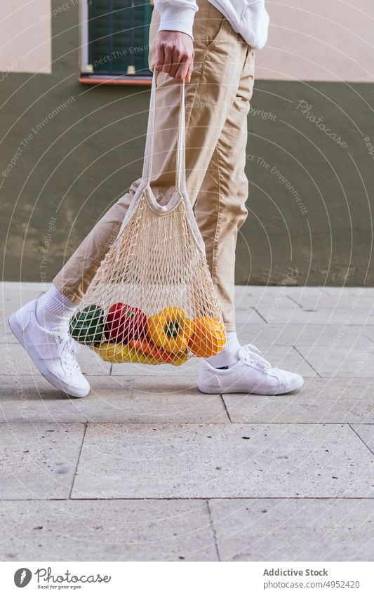 Anonymous man with fruits in mesh bag in city eco friendly street grocery natural zero waste male organic urban ripe fresh shopper shopping bag healthy food