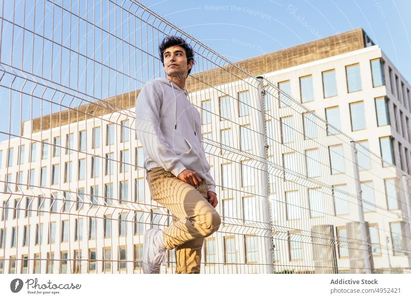 Stylish man standing near metal grid in city style fence trendy outfit urban content male young street confident personality handsome hipster cool appearance