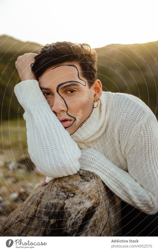Stylish man leaning on stone style ornament creative nature rest appearance concept male young ethnic model makeup countryside trendy fashion daytime sunny