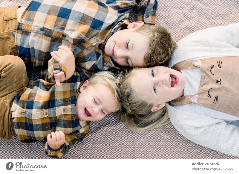 Cute positive little siblings lying on blanket in daylight children picnic brother sister together spend time alike childhood playful smile happy style blond