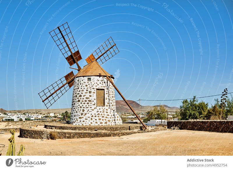 Old windmill on stone platform under blue sky tower energy power engine nature alternative produce island rotational construction blade large material