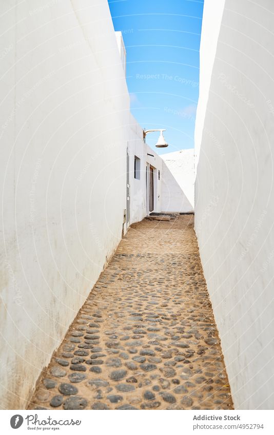 Narrow passage between white houses under blue sky cobblestone narrow building architecture rural pathway walkway facade exterior summer sunny canary resort