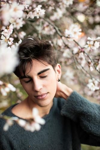 Young Man With Closed Eyes Under Blooming Tree nature tree outdoors model park flower almond bloom blossom blur botany branch calm elegant environment