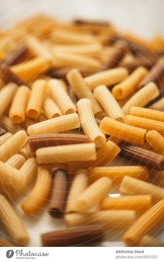 Assortment of colorful macaroni pasta uncooked raw food italian cuisine multicolored dark pale ingredient dry yellow healthy traditional cooking meal nutrition