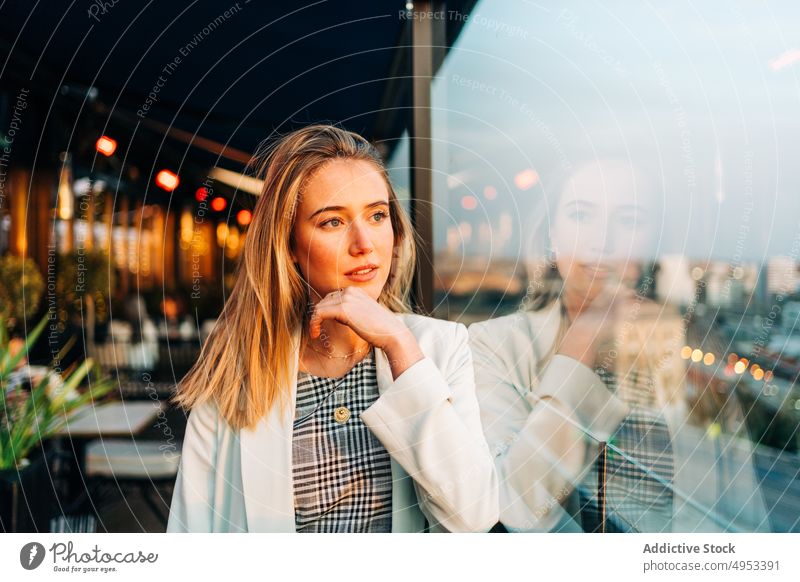 Dreamy woman standing in rooftop restaurant in evening dreamy cafe sunlight enjoy thoughtful female chill style relax glass window elegant sunset calm