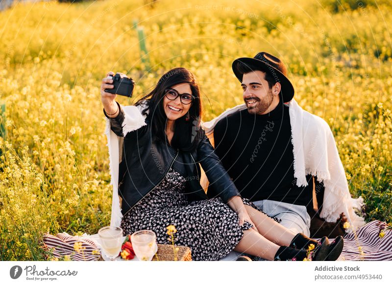 Happy ethnic couple taking selfie on photo camera in field memory moment happy romantic relationship meadow using device self portrait girlfriend boyfriend