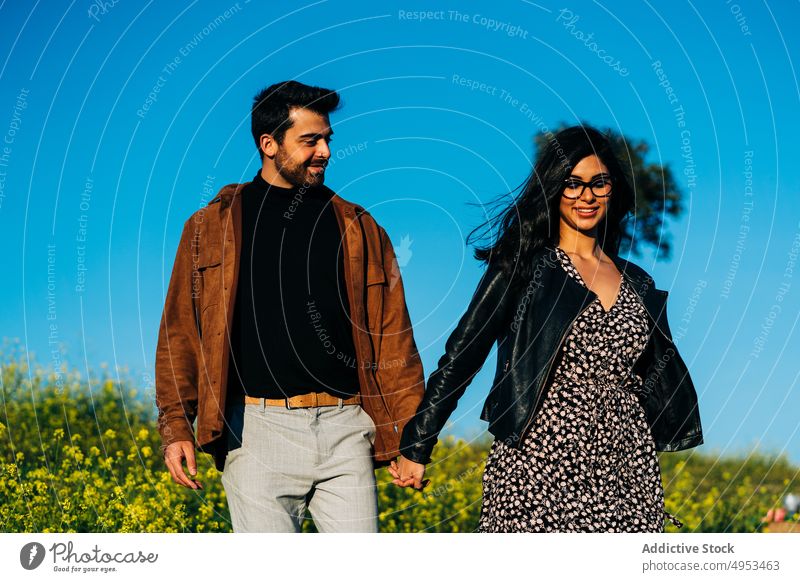 Ethnic couple spending time in countryside field relationship love spend time weekend walk holding hands soulmate nature blue sky romantic enjoy eyeglasses