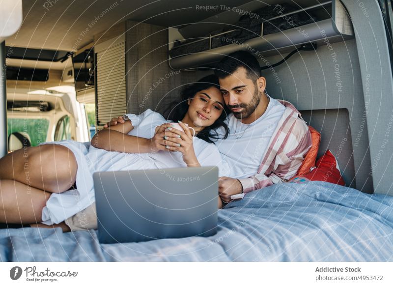 Hispanic traveling watching movie on laptop in van couple traveler camper work embrace cheerful caravan trip ethnic hispanic love bed together relationship