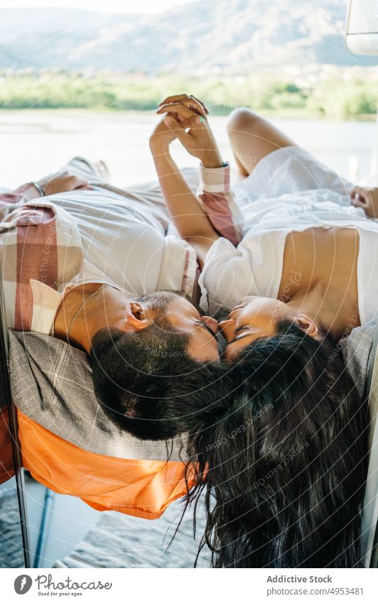 Loving Hispanic traveling couple lying on bed in van traveler love holding hands tender camper caravan enjoy ethnic hispanic relationship affection together