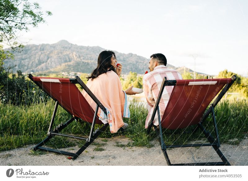 Traveling couple sitting in camping chairs in mountainous terrain travel campsite together adventure eat strawberry vacation nature enjoy relationship summer