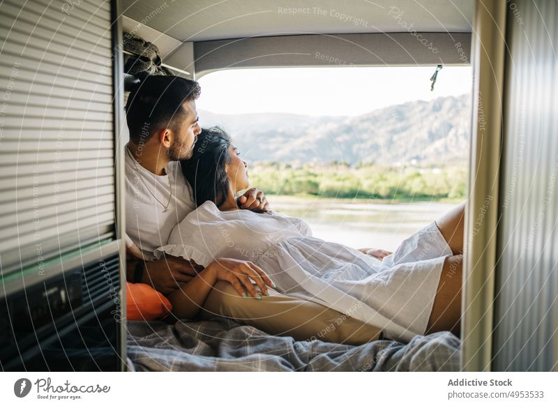 Loving ethnic couple of travelers lying in van bed caravan together camper tender hispanic love relationship girlfriend enjoy romantic trip boyfriend vacation
