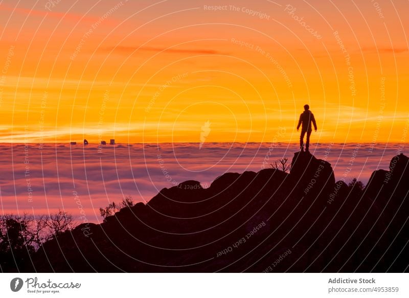 Man standing on high rock and looking at sunset silhouette clouds man mountain sky nature active extreme fog cliff top peak male challenge free courage freedom