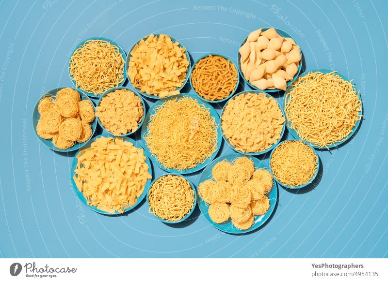 Pasta variety top view on a blue background. Raw pasta on blue plates. above assortment bowls bright carbs color cuisine different dry farfalle fettuccine