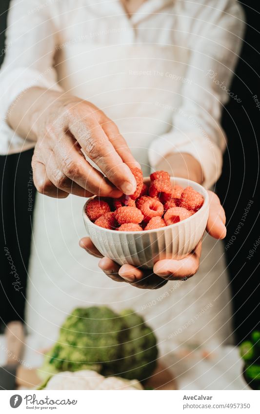 https://www.photocase.com/photos/4957350-woman-holding-a-cup-with-raspberries-and-showing-the-quality-in-close-up-dot-preparing-the-ingredients-for-a-sauce-to-improve-the-recipe-dot-black-background-with-white-clothes-and-broccoli-on-the-table-photocase-stock-photo-large.jpeg