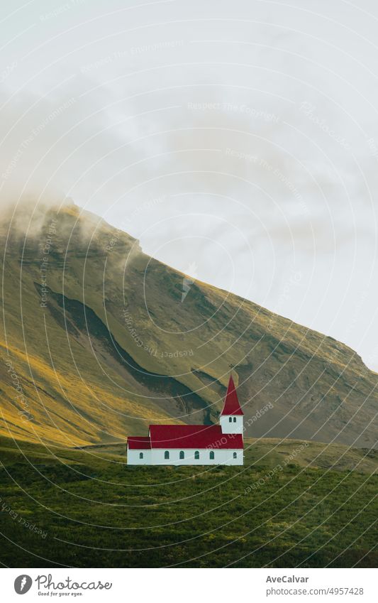 Landscape wallpaper of the Church of Vík í Mýrdal in Iceland in front of a massive mountain during the sunset. Copy space image, moody style. Visit Iceland, travel route on wastelands