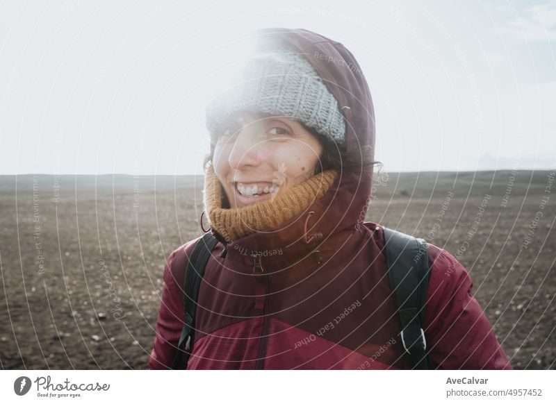 Woman on winter clothes smiling and laughing to camera while visiting Iceland, on the beach of Sólheimasandur. Travel to Iceland, road trip concept. Copy space image, visit Iceland.