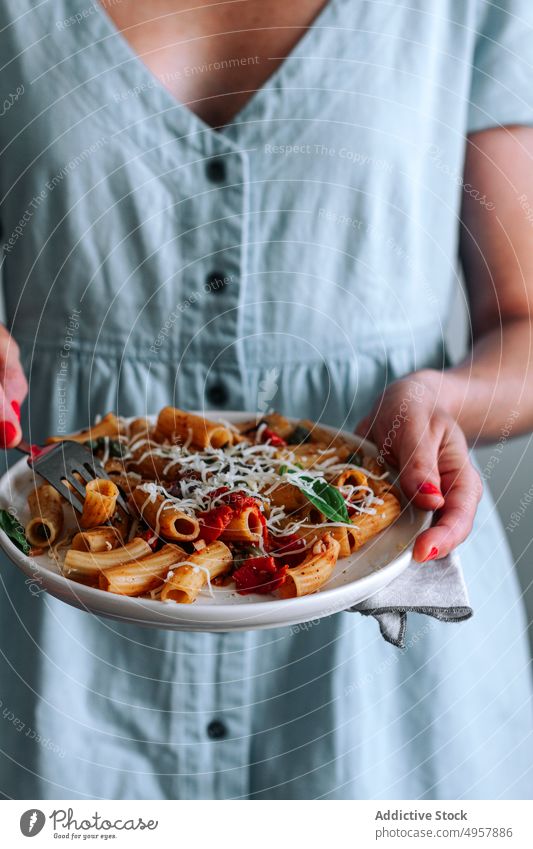 Anonymous Woman Holding Pasta Alla Puttanesca dish woman holding pasta puttanesca macaroni penne rigate lunch hands anonymous unrecognizable dinner basil