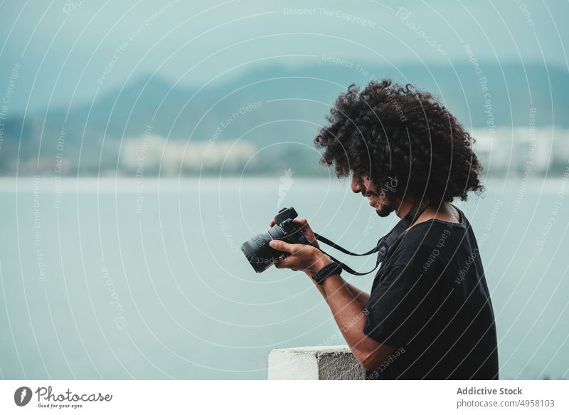 Black photographer taking photo of sea on professional camera take photo photo camera ocean focus digital memory man using device moment attentive lens
