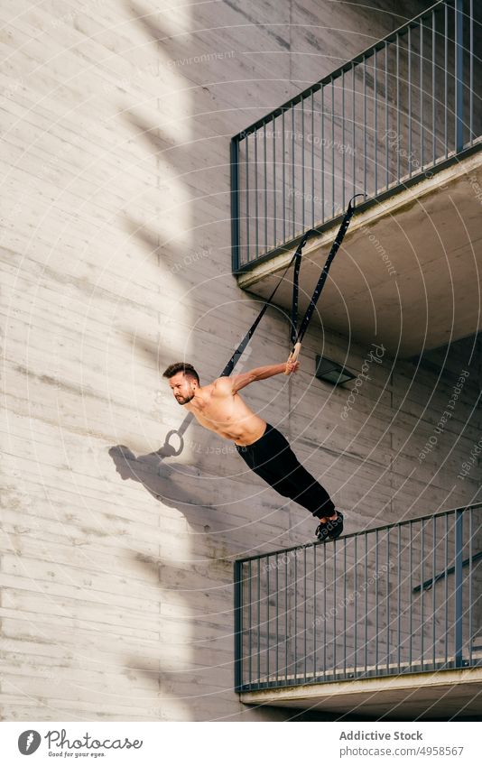 Athletic man balancing on gymnastic rings sportsman shirtless city athletic young active workout construction body lifestyle healthy male exercise fitness