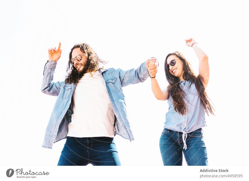 Happy ethnic couple in sunglasses dancing on white background holding hands dance having fun relationship cheerful lifestyle point up carefree romantic smile