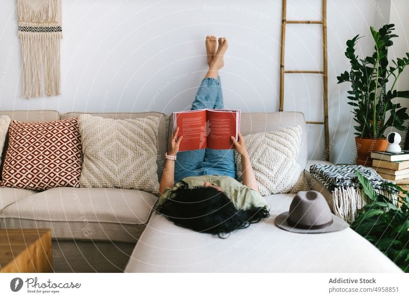Woman reading a book at home female couch woman sofa lifestyle young leisure girl relax beautiful caucasian indoors adult literature room people attractive