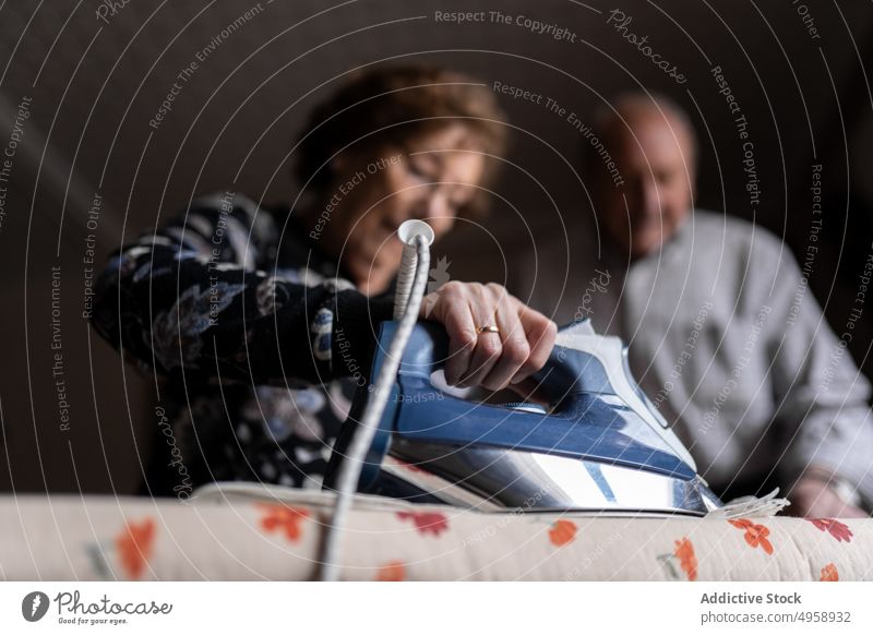 Elderly couple ironing clothes in room elderly aged senior chore housework routine mature focus home male concentrate casual domestic at home man woman wrinkle